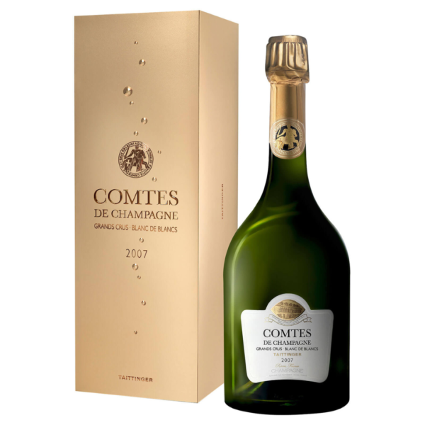 En flaske champagne står ved siden af en gylden æske. Tekst på æsken: "COMTES DE CHAMPAGNE GRANDS CRUS BLANC DE BLANCS 2007 TAITTINGER". Flasken har en lignende etiket.